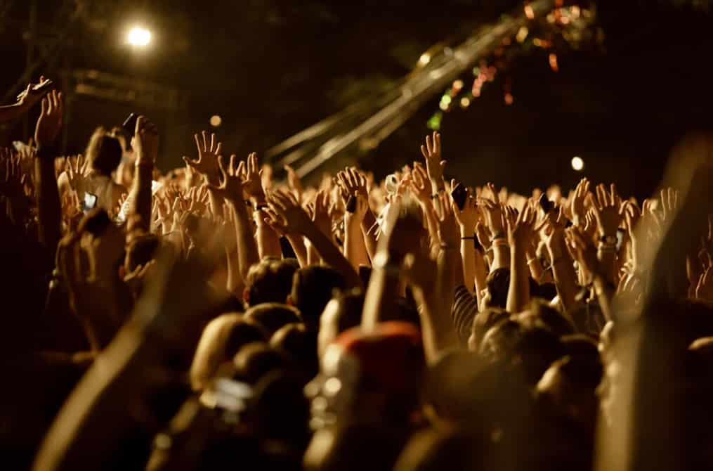 A crowd of people with raised hands enjoying a concert at night