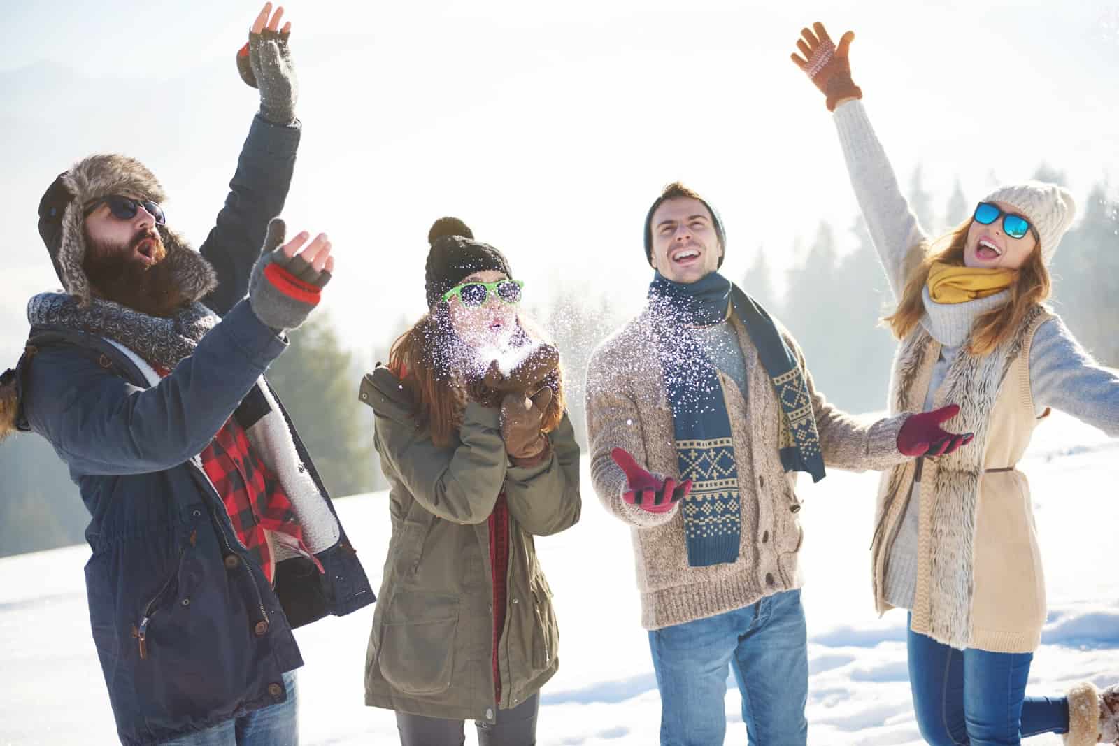 A group of people in warm clothes throw snow