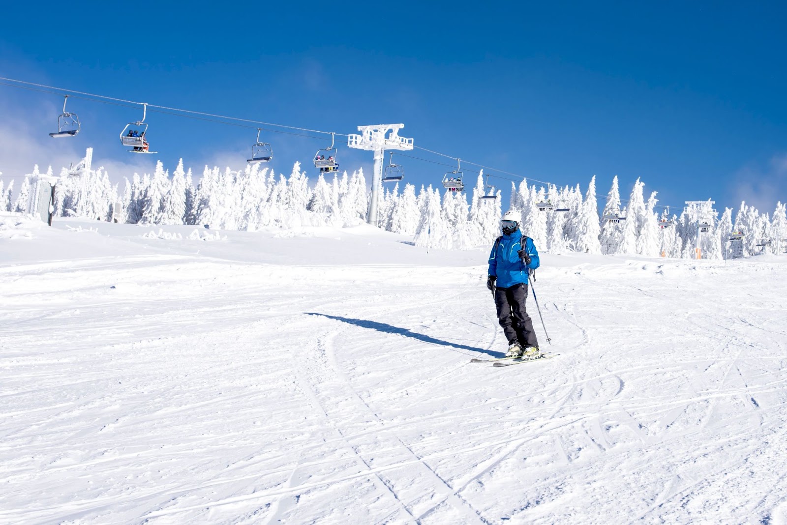 Skier riding down the hill in the mountain resort with cable cars in the background