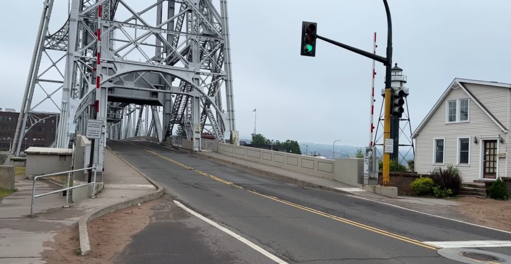 Lift bridge over a road with traffic lights and a white house beside it
